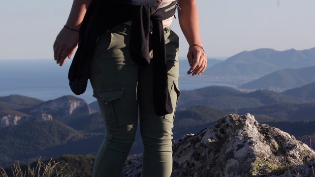 女性徒步者攀登岩石山脊以上的山脉，大海视频素材