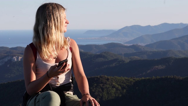 女性徒步旅行者在岩石山脊上放松的山脉，大海视频素材