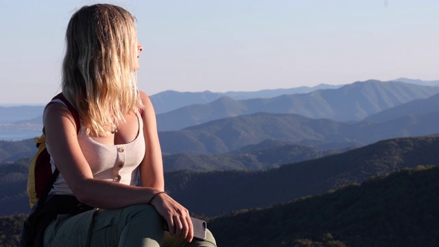 女性徒步旅行者在岩石山脊上放松的山脉，大海视频素材