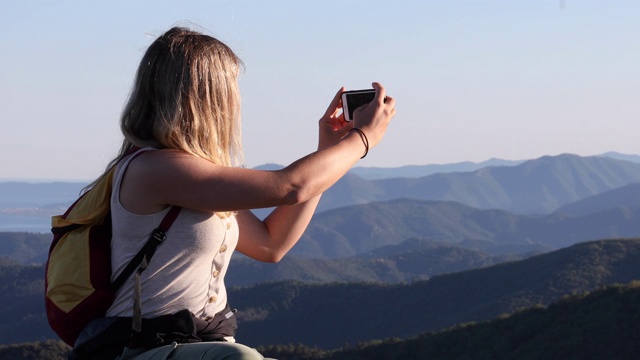 女性徒步旅行者在岩石山脊上放松的山脉，大海视频素材