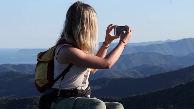 女性徒步旅行者在岩石山脊上放松的山脉，大海视频素材