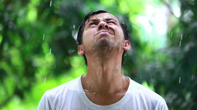 年轻人不开心的站在雨中，一个悲伤的人在雨中的肖像，糟糕的暴风雨下雨的天气概念视频素材画面4