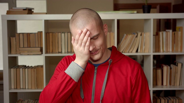 年轻的有吸引力的白人男学生的特写肖像做一个脸掌心被激怒看在大学图书馆室内的相机视频素材