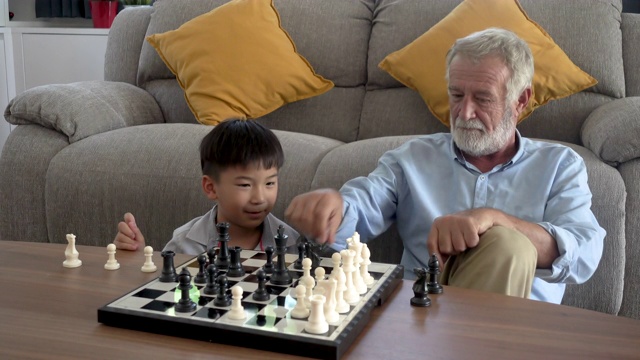 快乐的小男孩孙子和老爷爷在家里下棋视频素材