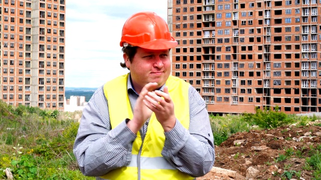 在建筑工地上，男建筑工头、工人或建筑师正在拍手，看着镜头视频素材