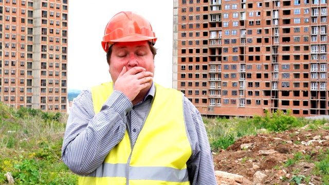 疲惫的男性建筑工头，工人或建筑师在建筑工地打哈欠视频素材