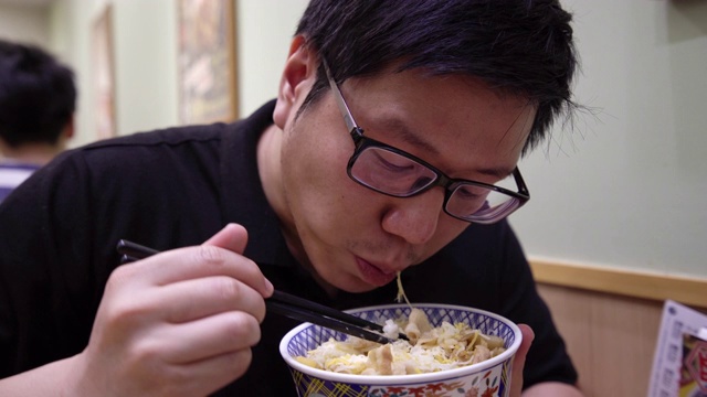 亚洲男子在餐厅吃日本牛肉碗。视频素材画面1