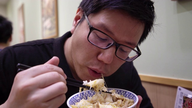 亚洲男子在餐厅吃日本牛肉碗。视频素材画面2