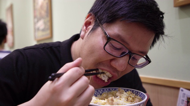 亚洲男子在餐厅吃日本牛肉碗。视频素材画面3