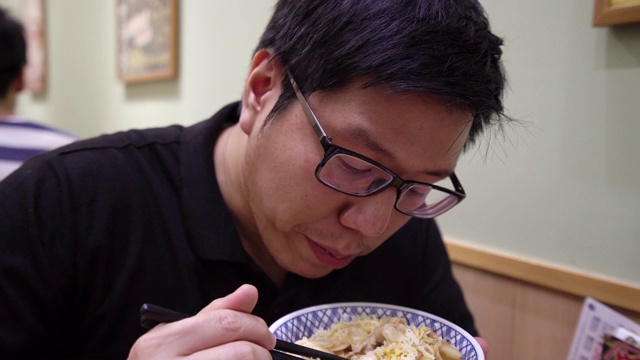 亚洲男子在餐厅吃日本牛肉碗。视频素材画面4