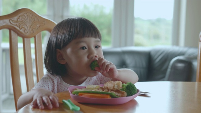 蹒跚学步的小女孩在家里吃西兰花视频素材画面4