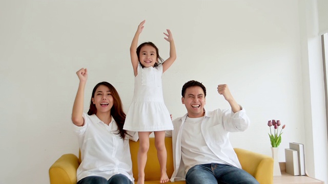 幸福的亚洲家庭一起在家看电视。三岁的爸爸、妈妈和女儿都喜欢看电视。慢动作120帧/秒视频素材画面2