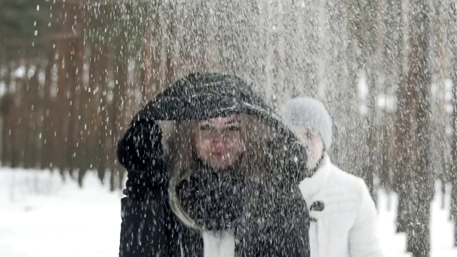 幸福的夫妇在森林里玩雪。年轻人把雪扔到头上。视频素材