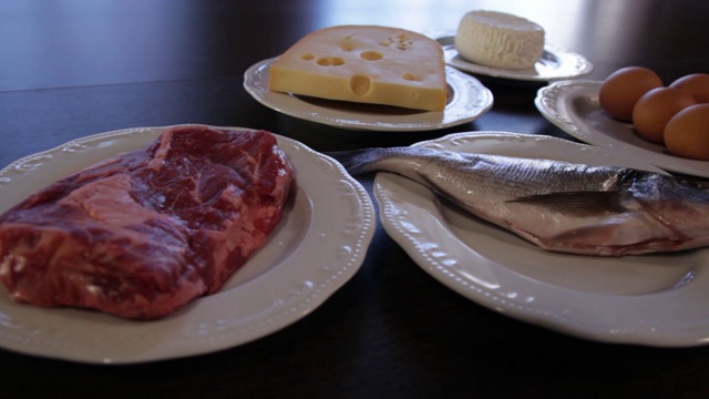 高蛋白的食物。生肉和鱼，奶酪，鸡蛋放在不同的盘子里。视频素材画面1