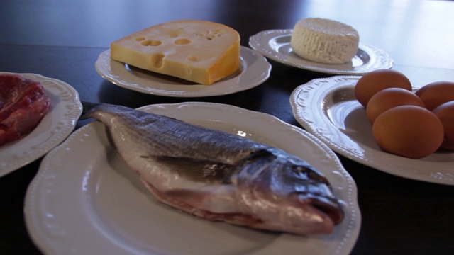 高蛋白的食物。生肉和鱼，奶酪，鸡蛋放在不同的盘子里。视频素材画面2