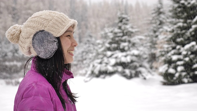 亚洲女人在冬天的森林里享受雪视频素材