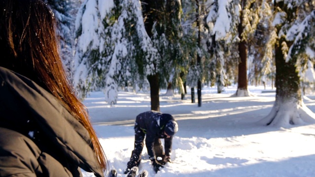 快乐的夫妇在冬天的森林里打雪仗和玩雪视频素材