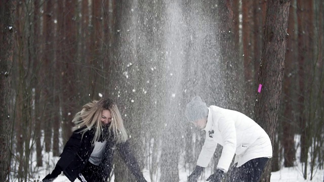 快乐的年轻人把雪扔到头上。快乐的夫妇玩雪视频素材