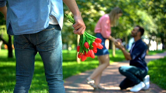 孤独的男人拿着花看着男人向心爱的女孩求婚视频素材