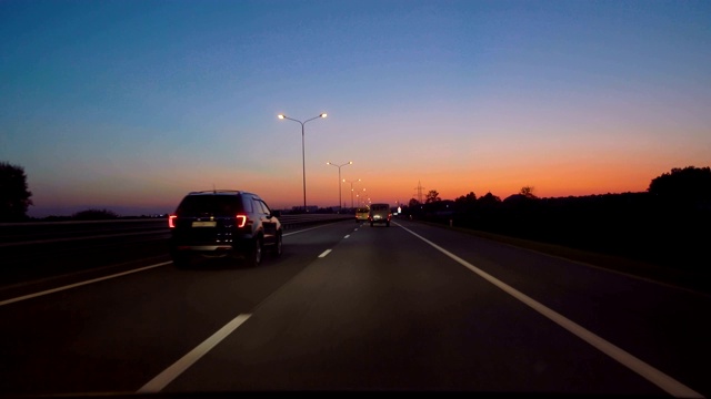 驾驶汽车POV在高速公路在夜晚在小交通后日落。傍晚日落街灯。夜，前摄像头，挡风玻璃参考。在高速公路上驾驶汽车在黑暗4K POV。视频素材