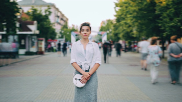 放大时间流逝，严肃的女人在休闲服装站在繁忙的街道视频素材画面2
