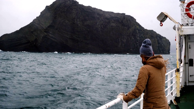 年轻美丽的女子站在大海中的船上。在阴天里独自探索冰岛的女性旅行者视频素材