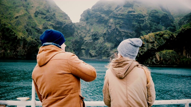 年轻的旅游夫妇站在船上聊天，欣赏冰岛美丽的风景。视频素材