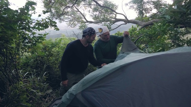 两名露营者在森林露营中安装帐篷，休息与自然融为一体。视频素材