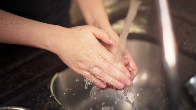 女人的手在厨房水龙头下洗西红柿的慢动作镜头。视频素材