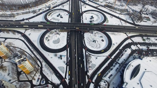 无人机拍摄冬季城市高速公路路口行驶的汽车。下雪的城市景观视频素材