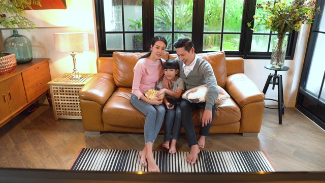 一个家庭在家里的沙发上看电视的高角度正面视图视频素材画面3