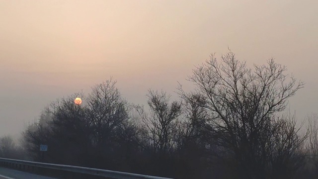 驾驶汽车的观点在一个冬天早晨雾蒙蒙的道路与太阳视频素材