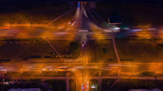 在照明路口的夜间汽车交通。现代城市夜间道路交汇处行驶的汽车发出的灯光。汽车在夜间城市的高速路口行驶视频素材