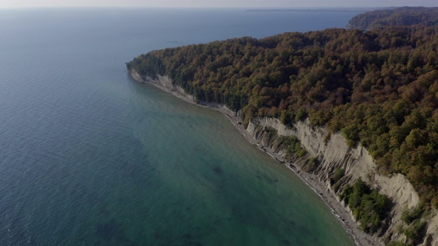 美丽的风景，丰富多彩的森林，悬崖，海岸鸟瞰图。光滑的水面透明的海水在悬崖海岸和森林在山景观无人机视图视频素材