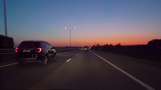 在高速公路上驾驶汽车在黑暗4K POV。傍晚日落街灯。夜，前摄像头，挡风玻璃参考。驾驶汽车POV在高速公路在夜晚在小交通后日落。视频素材