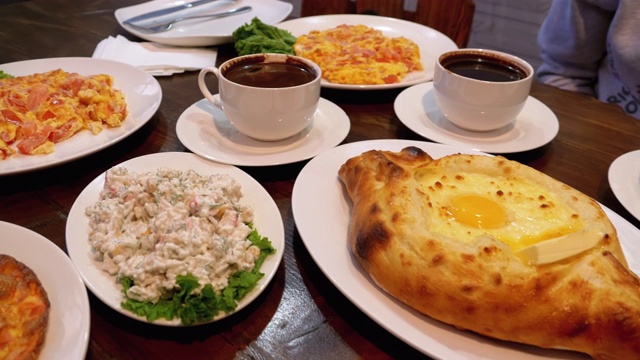 格鲁吉亚餐厅里的阿贾利安·哈切布里(Adjarian Khachapuri)，旁边是沙拉、煎蛋卷和咖啡视频素材