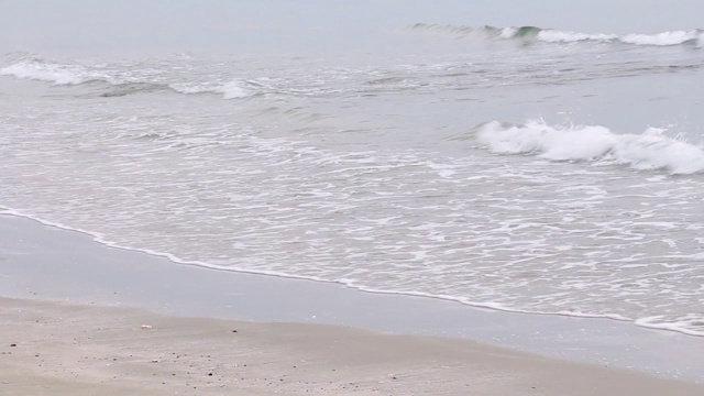 阳光在早晨随着海浪慢慢地溅在沙滩上，岩石上长满了苔藓。热带海滩宁静的田园风光。视频素材