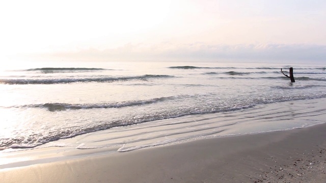 阳光在早晨随着海浪慢慢地溅在沙滩上，岩石上长满了苔藓。热带海滩宁静的田园风光。视频素材