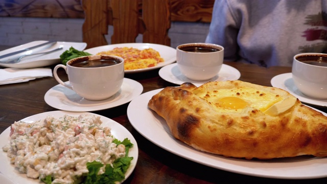 格鲁吉亚餐厅里的阿贾利安·哈切布里(Adjarian Khachapuri)，旁边是沙拉、煎蛋卷和咖啡视频素材