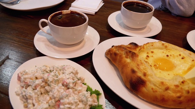 格鲁吉亚餐厅里的阿贾利安·哈切布里(Adjarian Khachapuri)，旁边是沙拉、煎蛋卷和咖啡视频素材