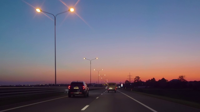 在高速公路上驾驶汽车在黑暗4K POV。傍晚日落街灯。夜，前摄像头，挡风玻璃参考。驾驶汽车POV在高速公路在夜晚在小交通后日落。视频素材