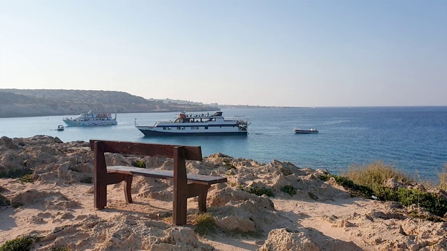 格列柯角(Cape Greco)观景台，位于海岬边缘的木凳，俯瞰大海和游船视频素材