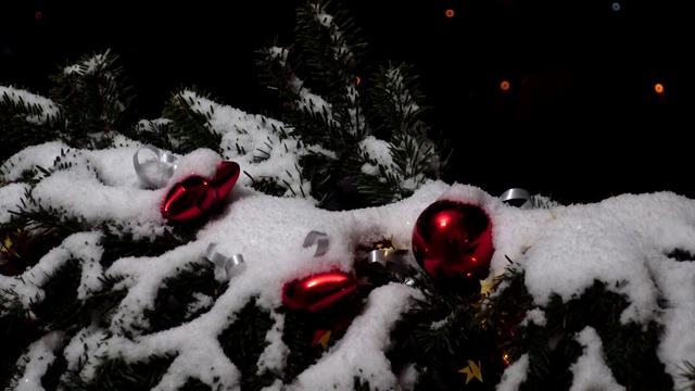 圣诞树的树枝上装饰着雪下的玩具。以夜城为背景，在夜晚拍摄。视频素材画面2