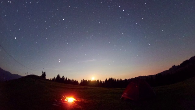 在繁星点点的天空下，日夜交替着露营帐篷和篝火视频素材