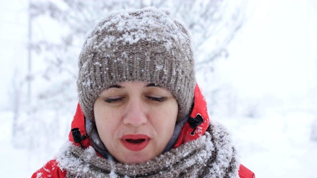 冬季娱乐的概念。女人正开心地吹着手中的新雪。视频素材