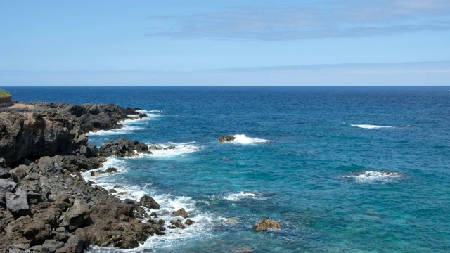 岩石海岸在一个阳光明媚的日子-海岸与黑色的岩石悬崖和海洋地平线视频素材