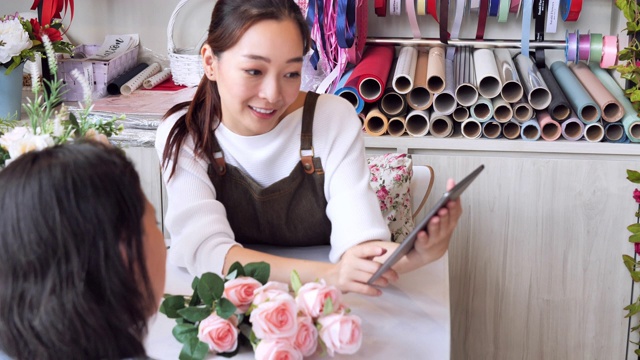亚洲女人接到订单准备进店销售，日本女人拥有专业的花店，小的经营理念。视频素材画面3