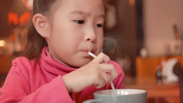 可爱的亚洲小女孩通过吸管喝水视频素材