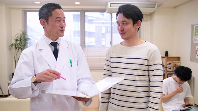 微笑的日本男医生安抚男性病人视频素材画面1