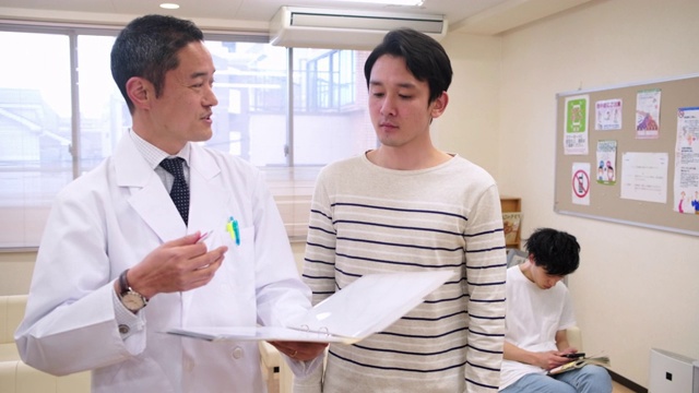 微笑的日本男医生安抚男性病人视频素材画面2